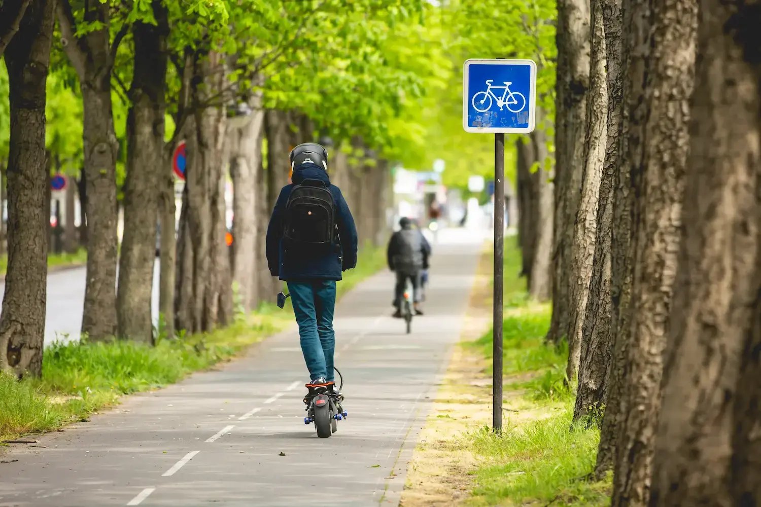 A person riding an electric scooter on a bike lane.