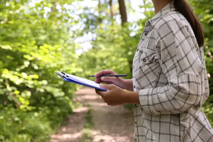 A volunteer in a park with a clipboard and pencil